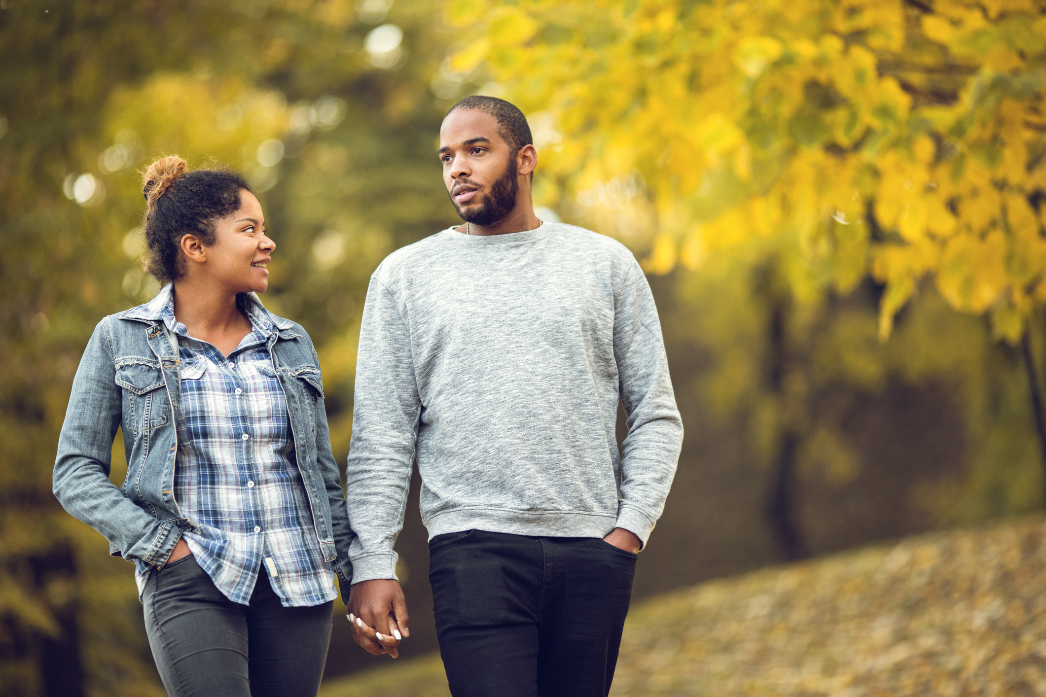 Young black couple holding hands and taking a walk in autumn day.