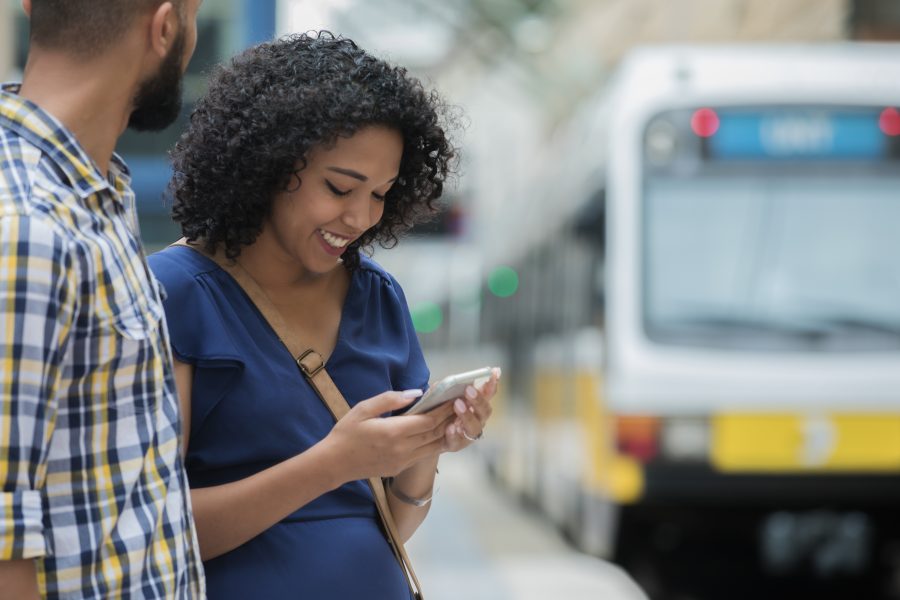 A train pulls into the station while a Young commuter couple uses smart phone