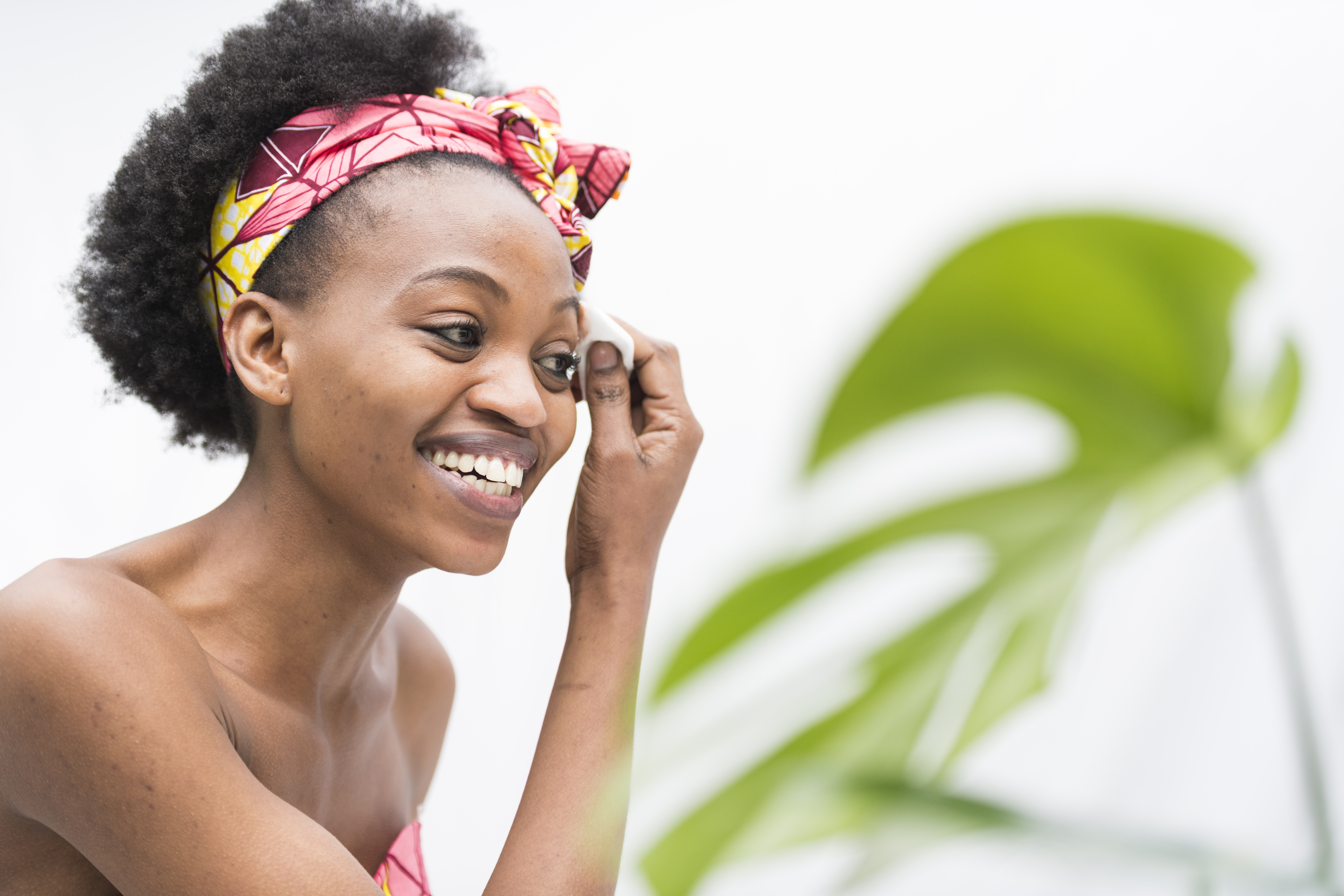 Smiling young African woman removing make up with cotton swab