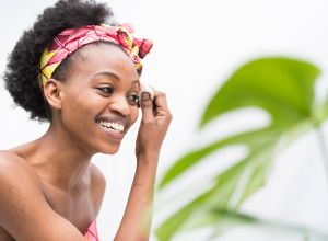 Smiling young African woman removing make up with cotton swab