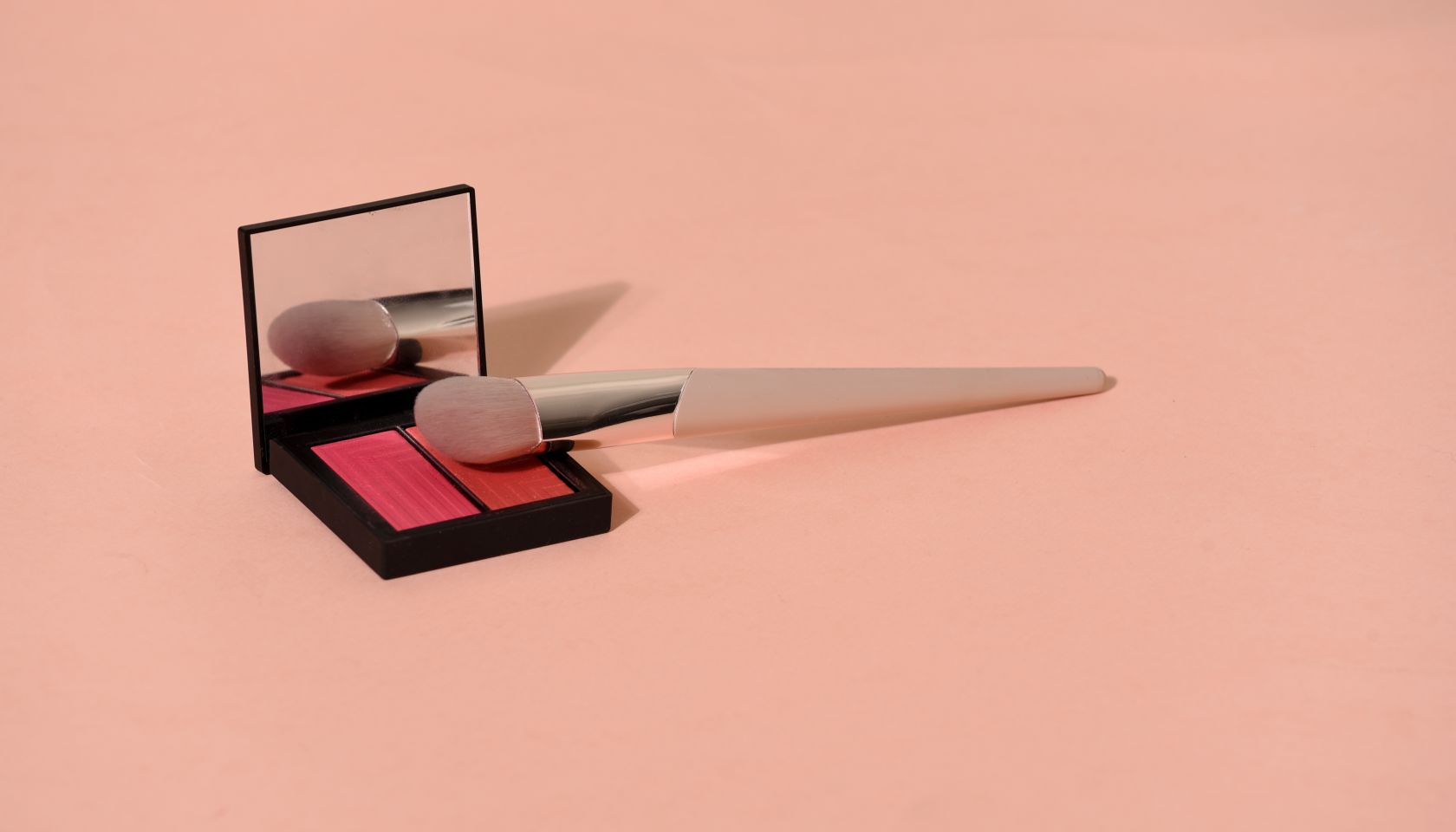 Close-Up Of Blusher With Make-Up Brush On Colored Background
