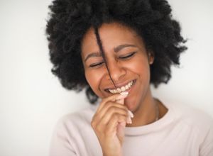 Smiling Black woman playing with hair