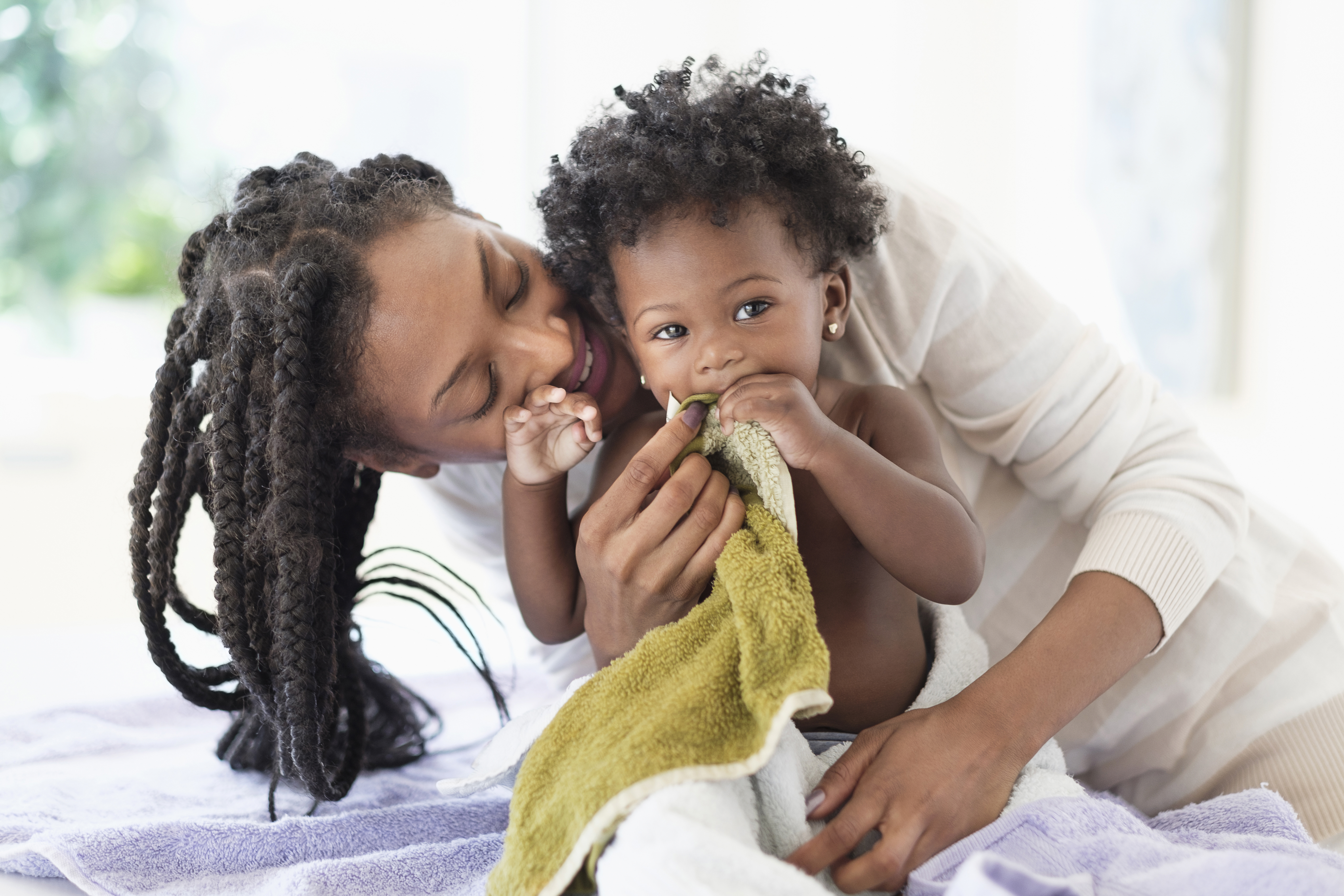 Black woman drying baby daughter with towels