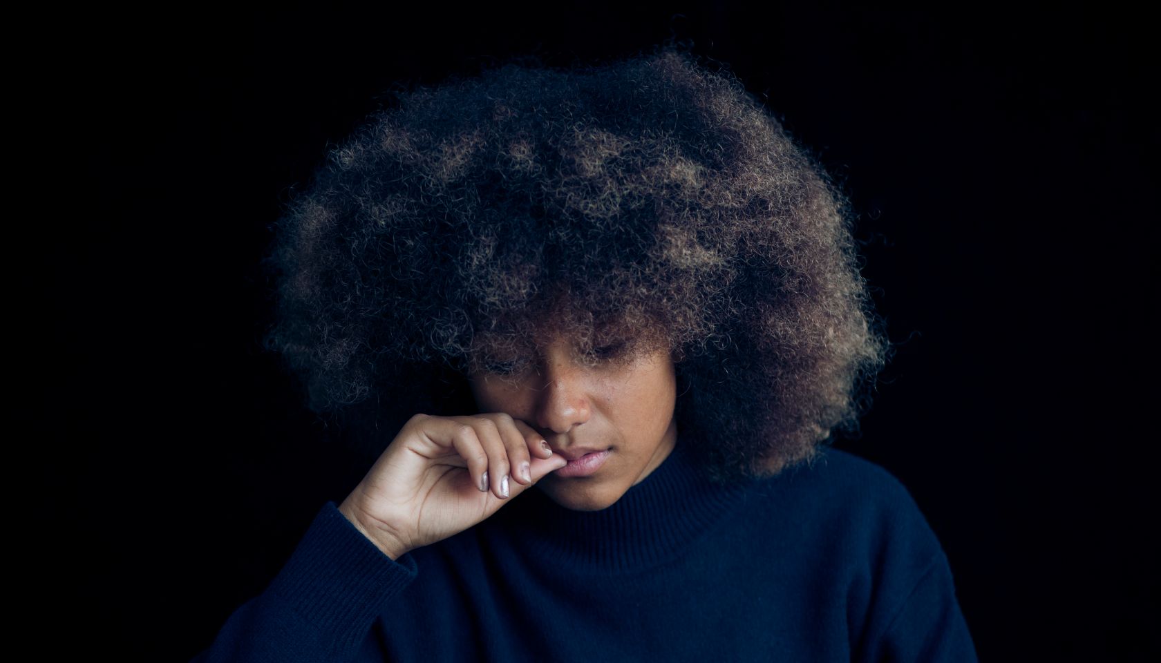 Mixed race teenage girl wearing a blue jumper with an afro haircut