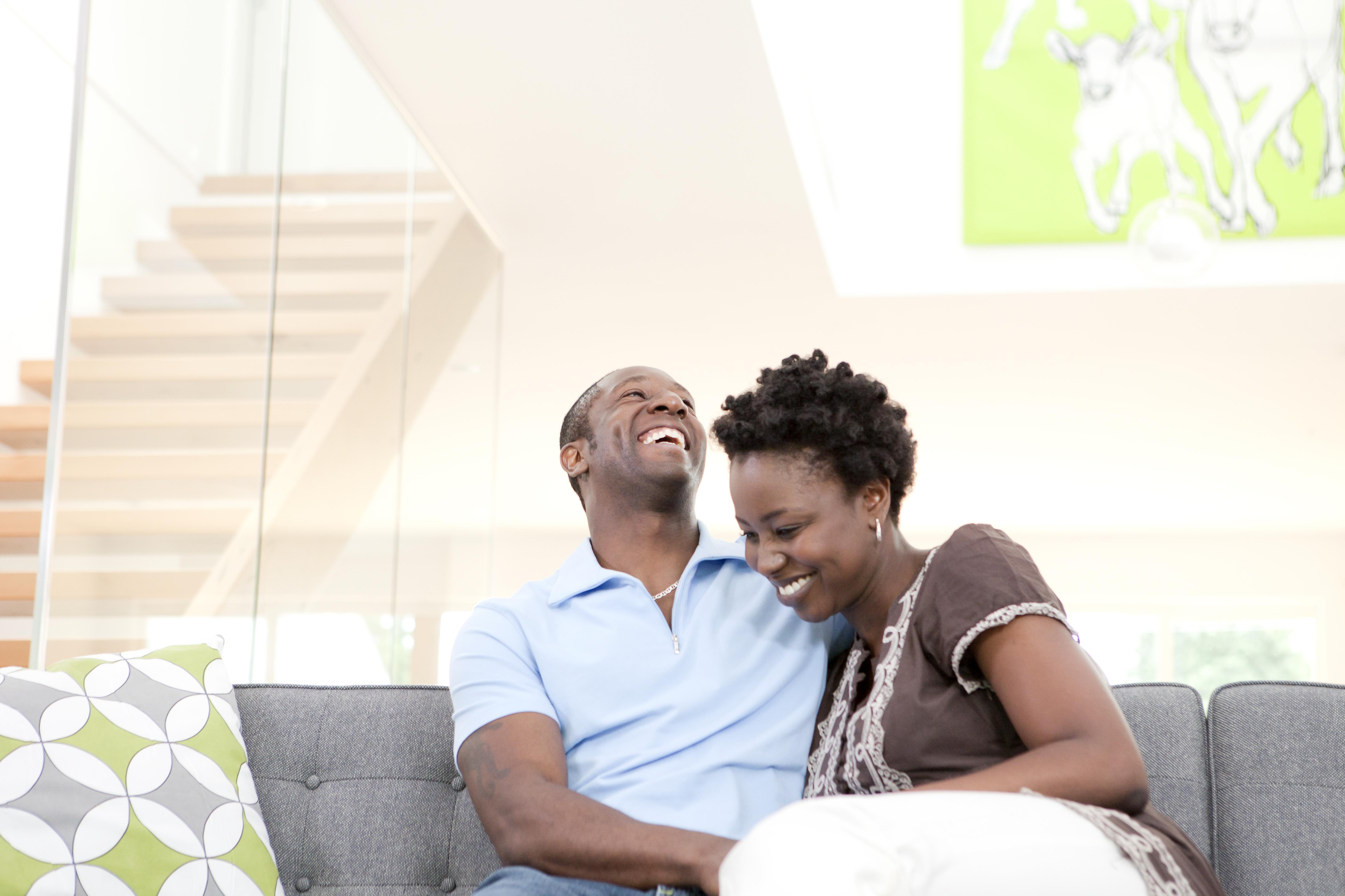 Laughing couple sitting on sofa in living room