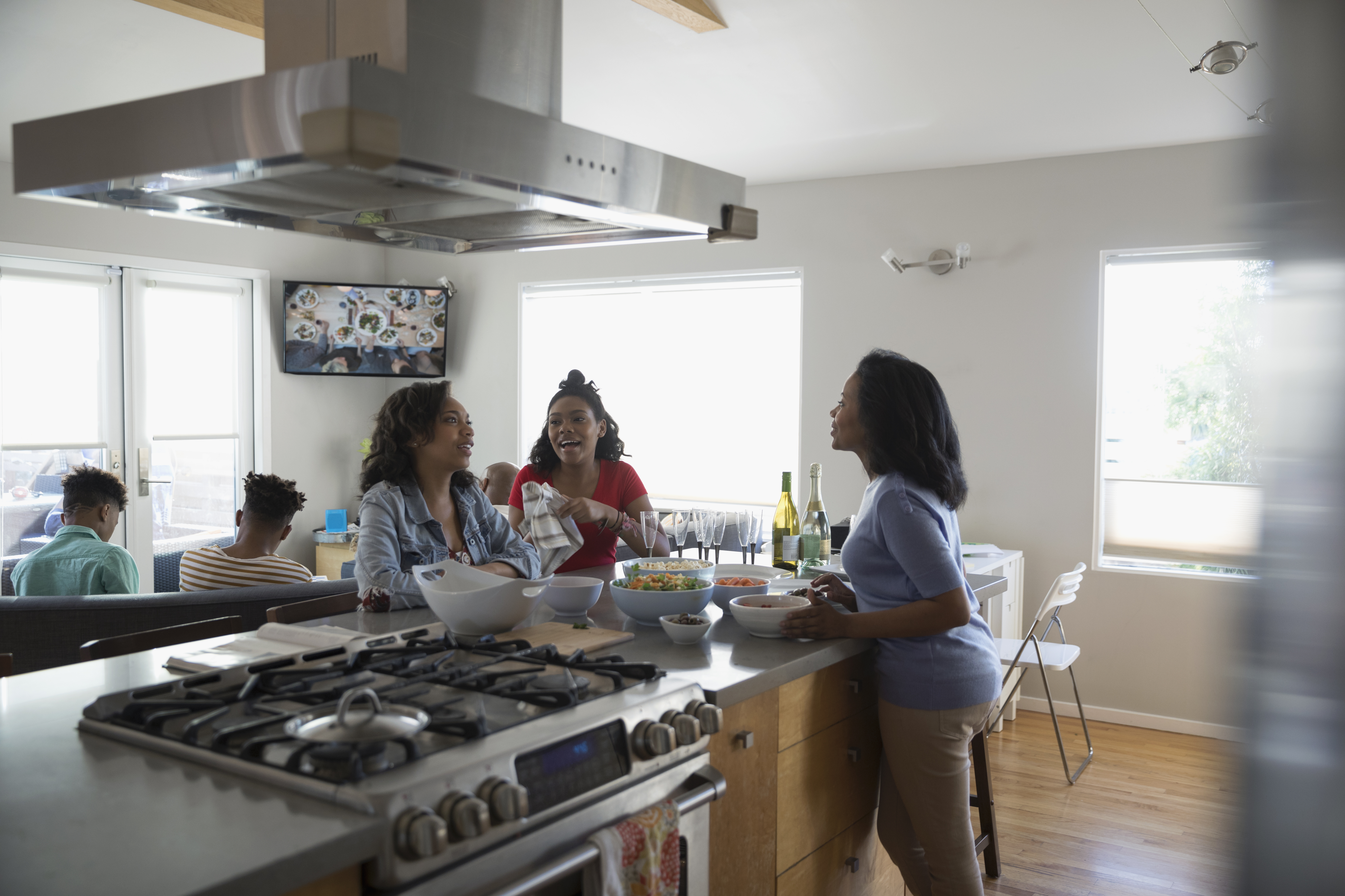African American mother and teenage daughters cooking and eating in kitchen