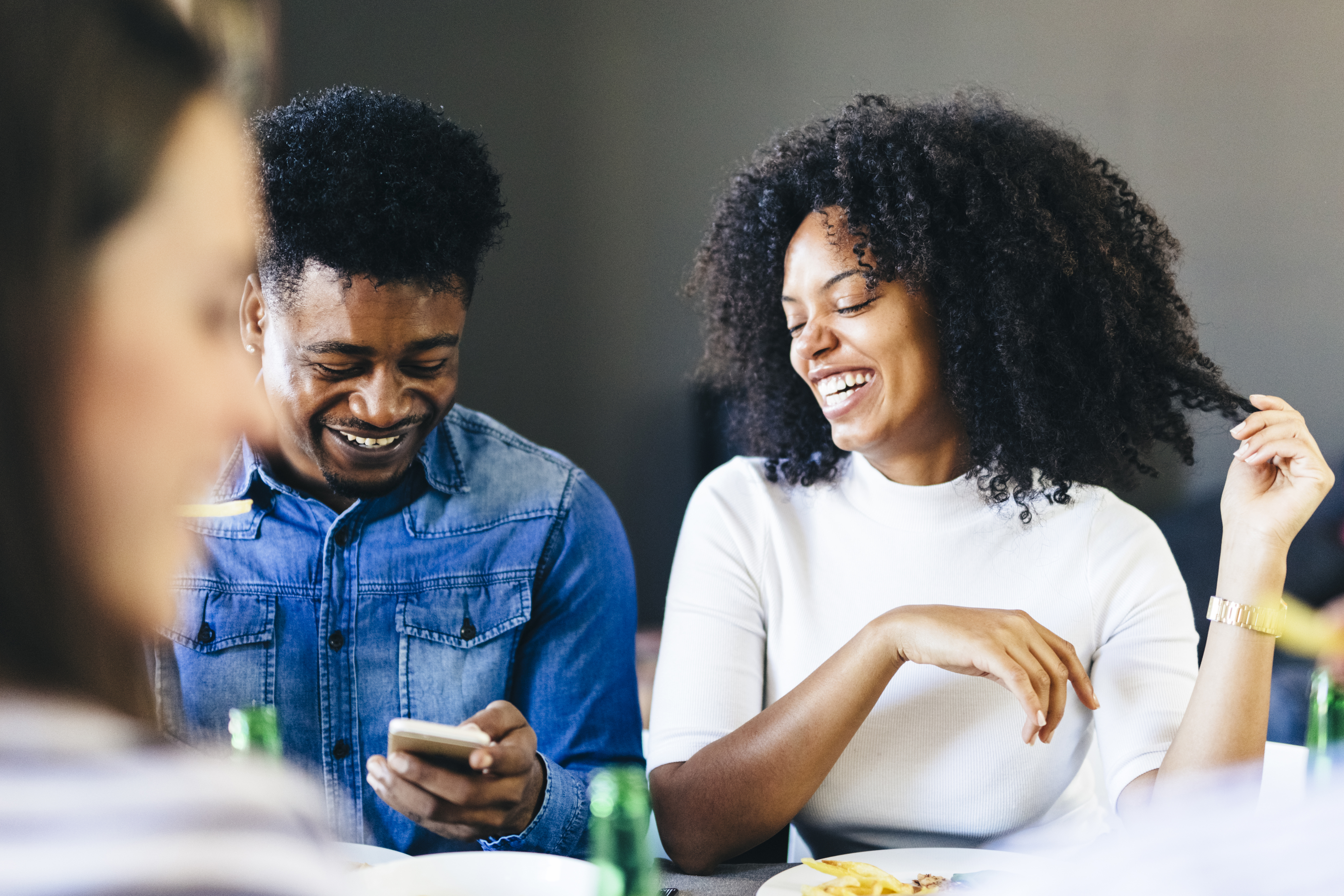Couple heureux partageant un téléphone portable à la table à manger