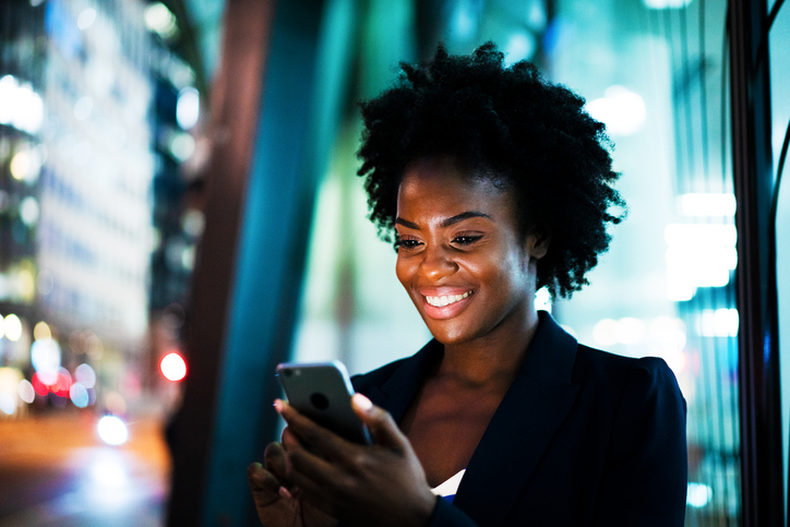 Woman using smart phone at night and smiling