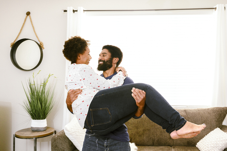Man carrying woman in living room