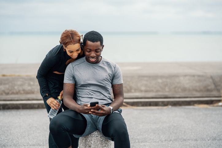 Young couple looking at a smart phone before or after running or jogging