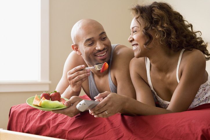 African couple eating in bed