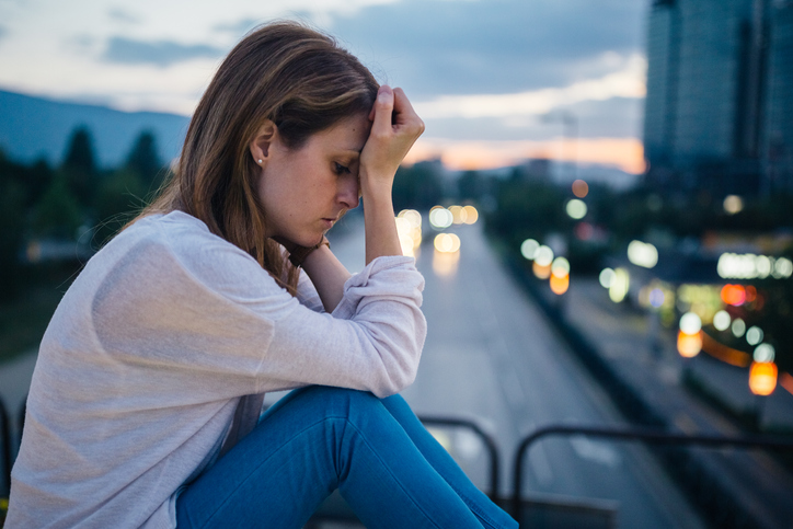 Depressed woman sitting lonely at the bridge