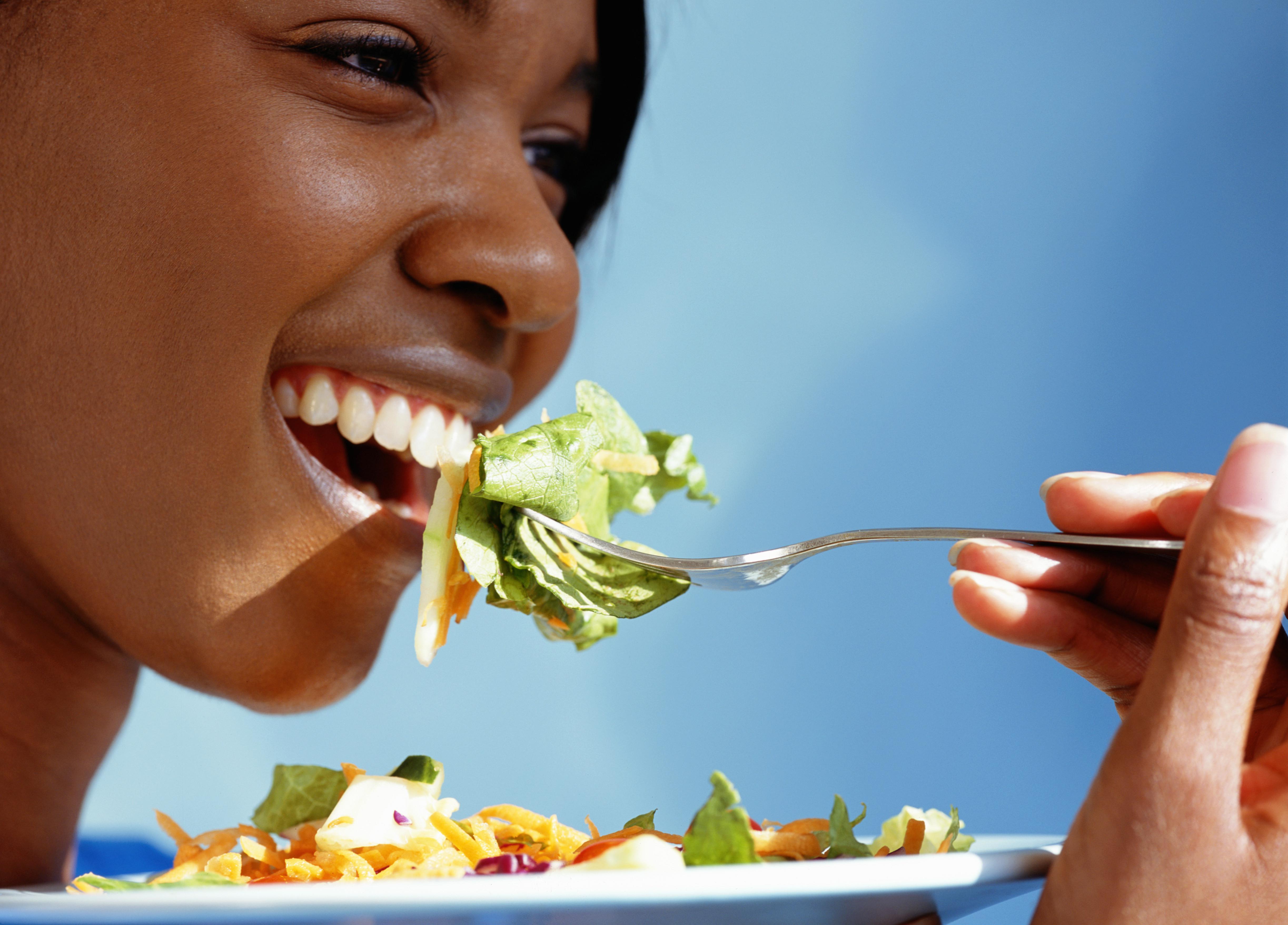 Young woman eating salad, close-up, side view