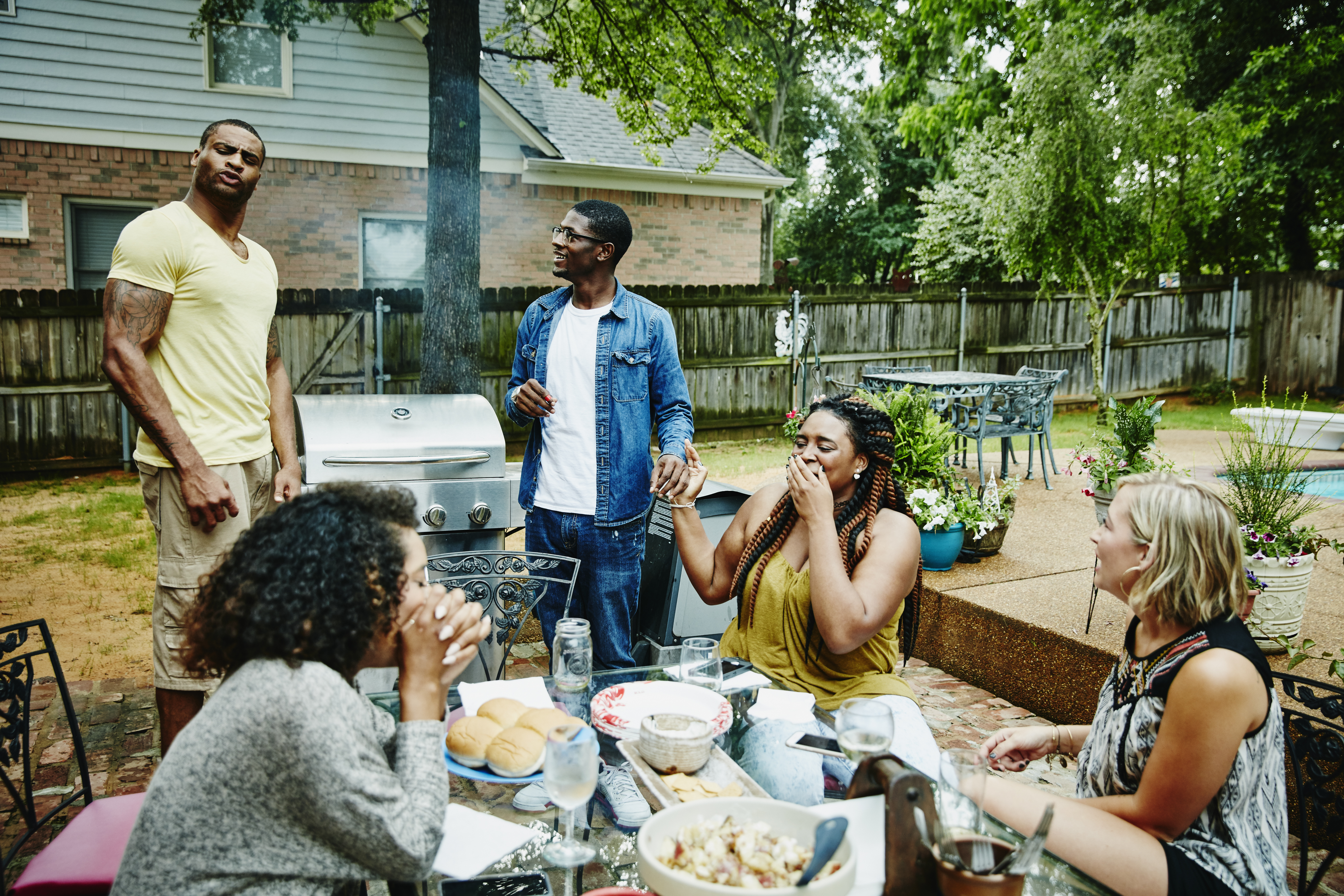 Laughing group of friends barbecuing in backyard