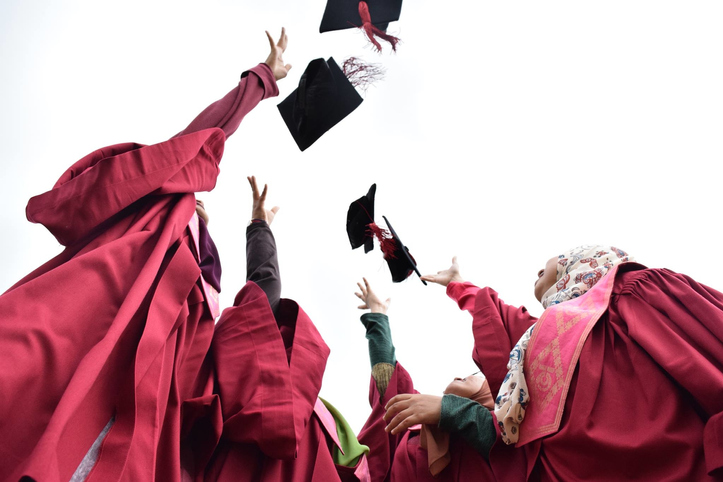 Low Angle View Of Students Throwing Mortarboard Against Sky