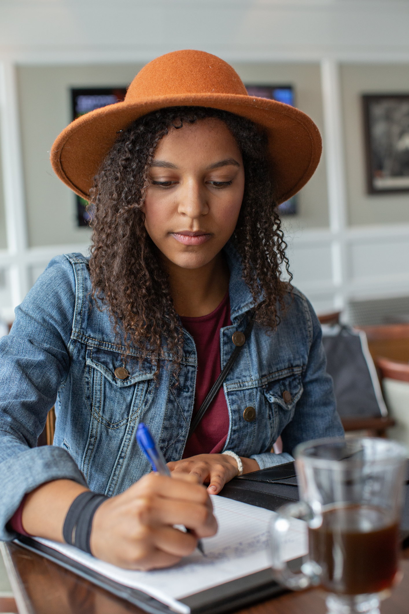 Young mixed race woman writes on note pad in airport coffee shop.
