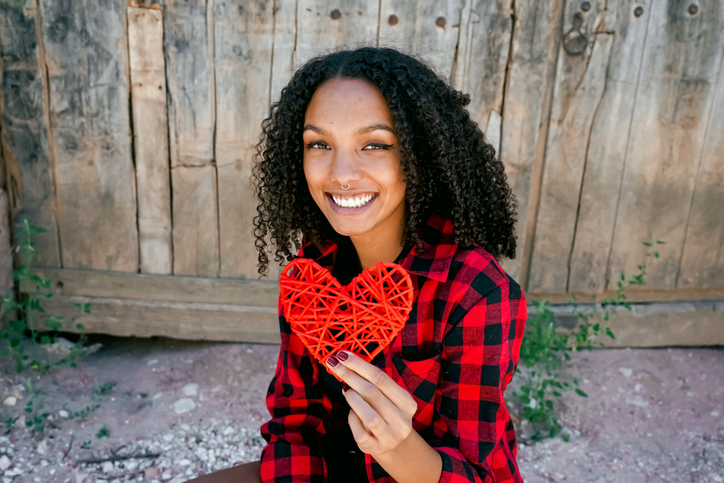 Portrait Of Smiling Young Woman Holding Heart Shape