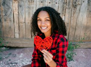 Portrait Of Smiling Young Woman Holding Heart Shape