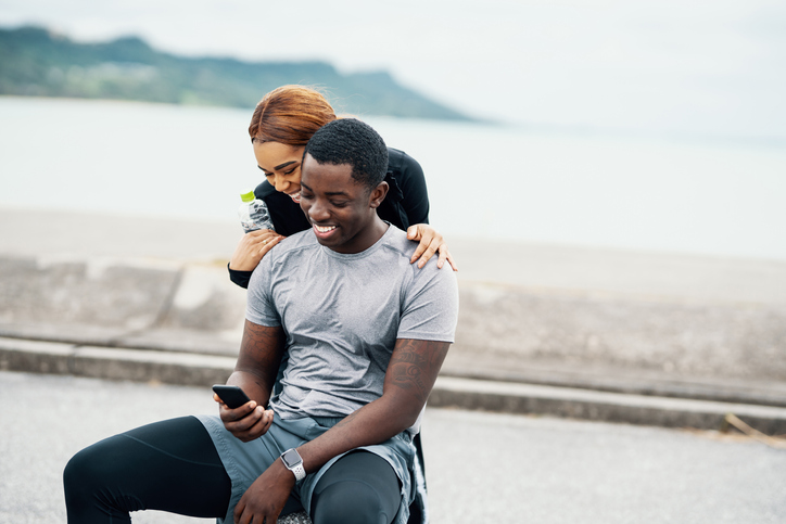 Young couple looking at a smart phone before or after running or jogging