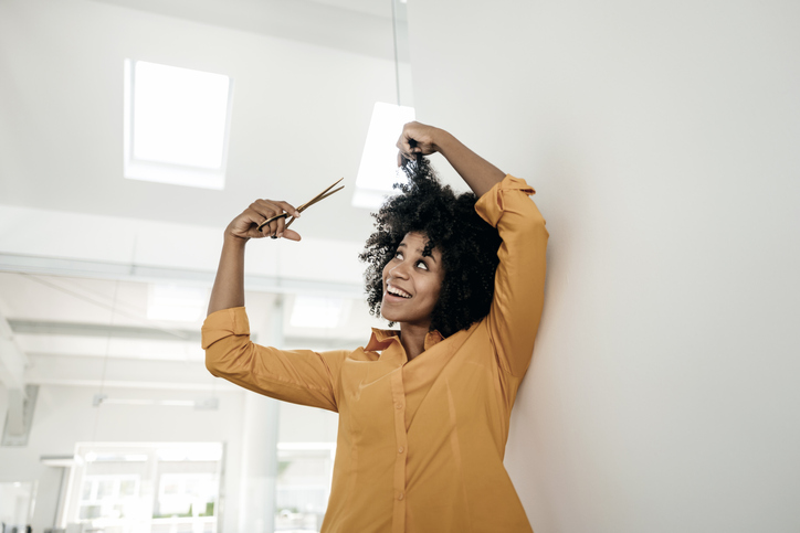 Smiling young woman cutting her hair