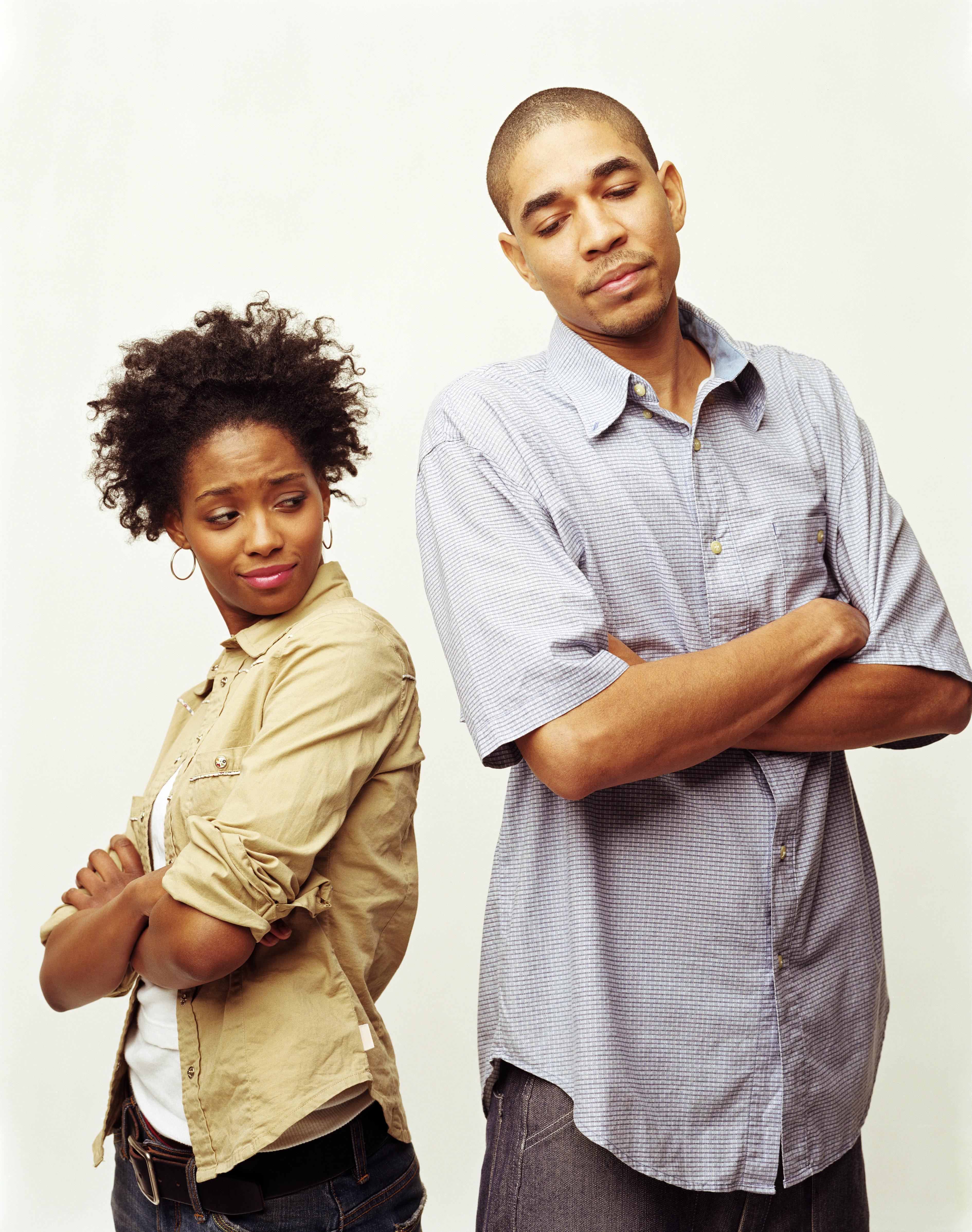 Young couple standing apart, crossing arms on chests