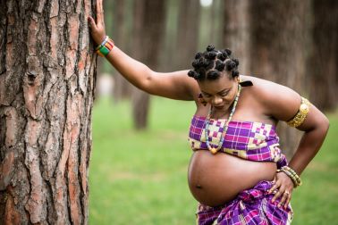 Pregnant Woman Standing Against Trees In Forest