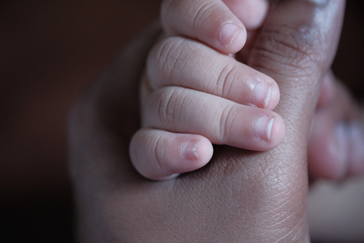 baby child holding finger of father