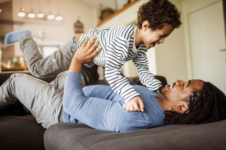 Happy black boy having fun with his father at home.