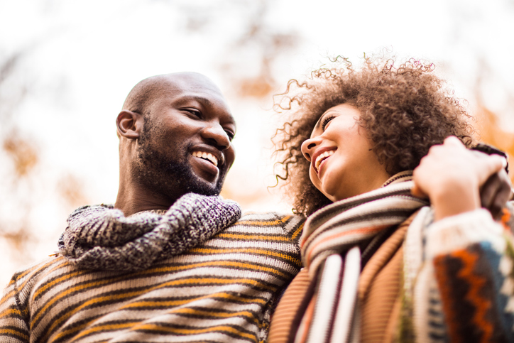 Below view of embraced African American couple talking in autumn day.