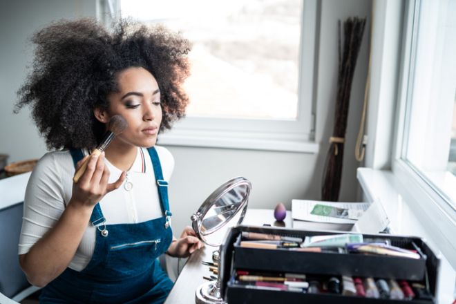 Young afro woman applying makeup at home