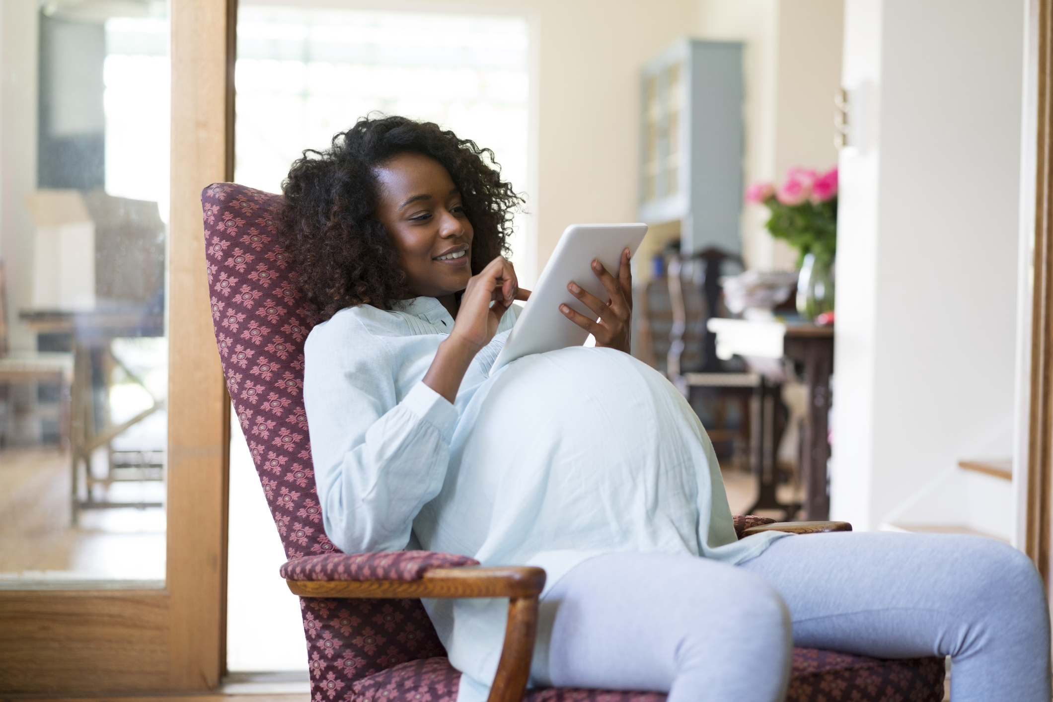 Pregnant woman using digital tablet at home - stock photo