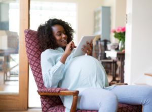 Pregnant woman using digital tablet at home - stock photo