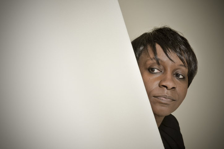 Middle age, African-American woman, 44 years old, looking around a corner