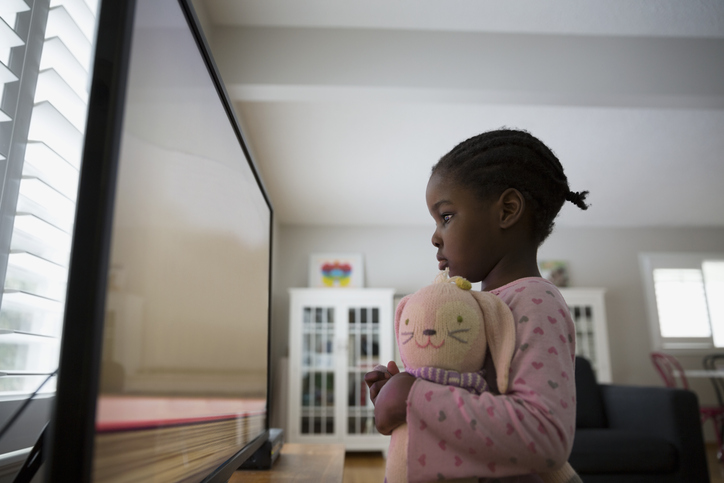 Girl with stuffed doll watching cartoons at TV
