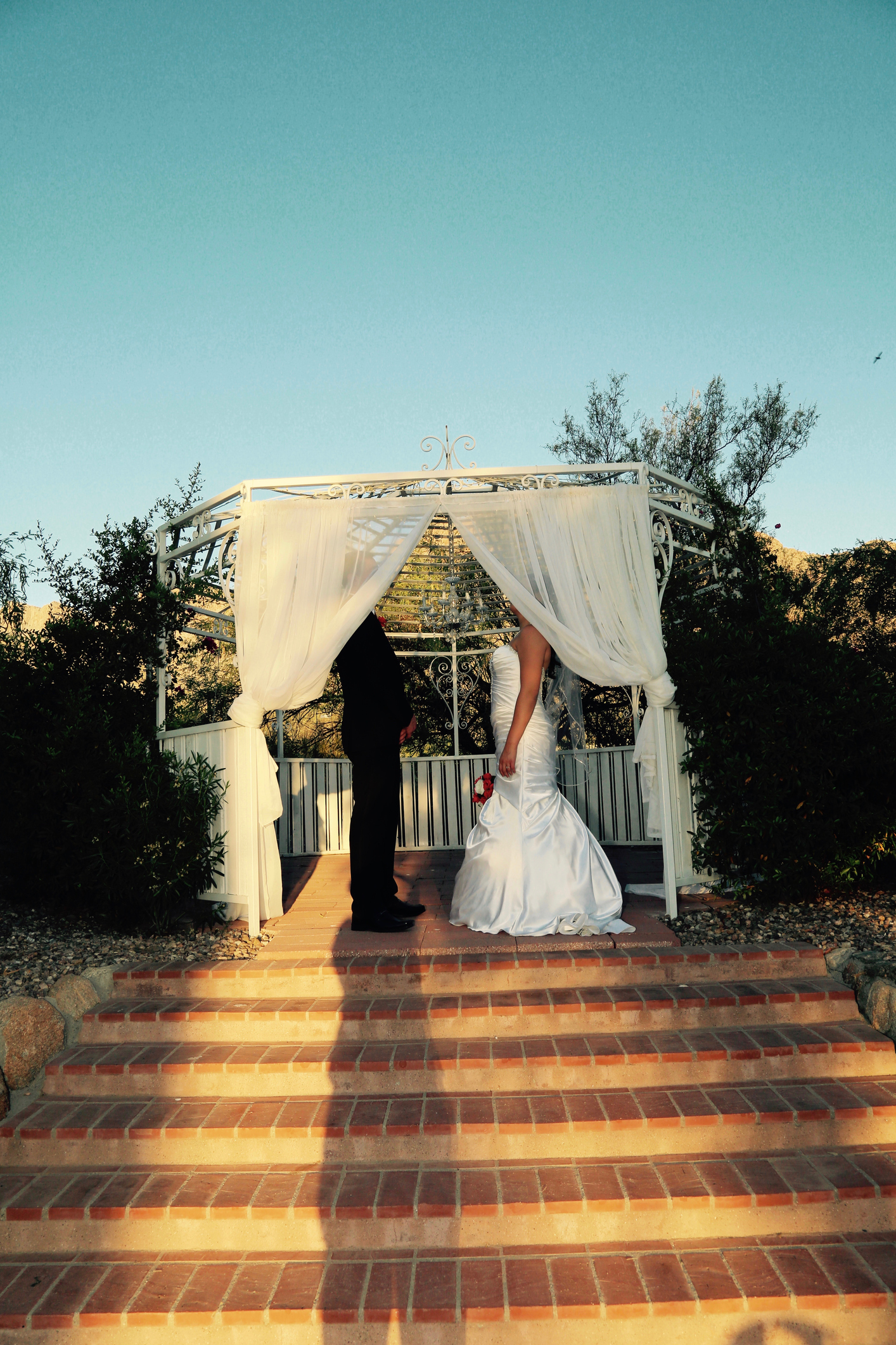 Bride and groom in a gazebo, faces behind curtains
