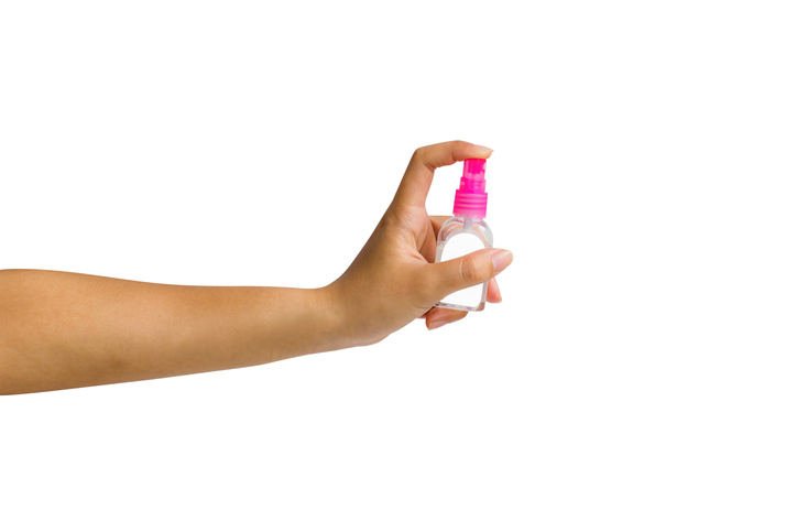 Close-Up Of Woman Holding Hand Sanitizer Against White Background