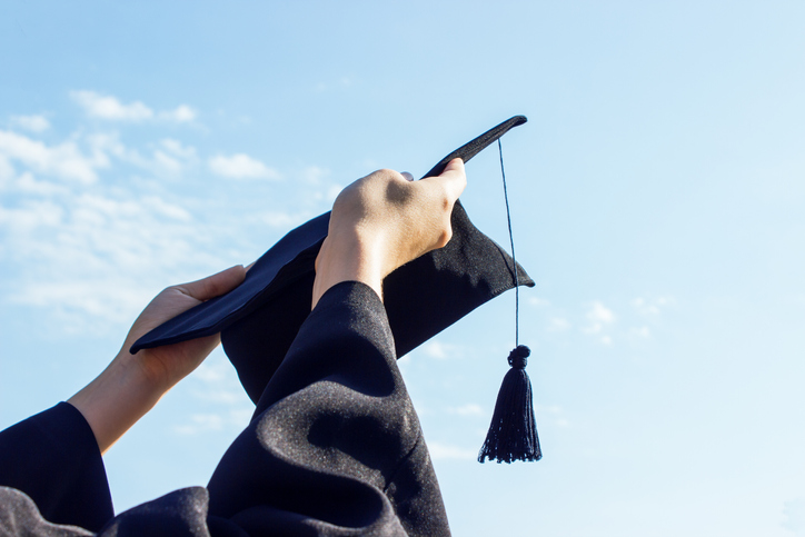 Low Angle View Of Hands Holding Mortarboard Against Sky During Sunny Day