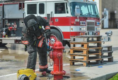 Firefighter opening a fire hydrant in front of a fire truck