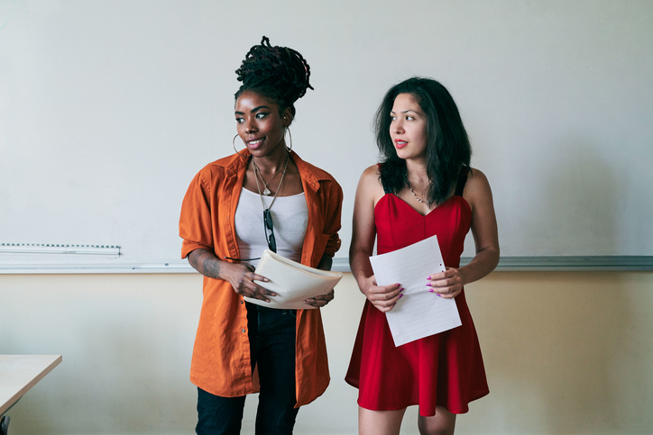 Female teachers looking away while holding documents in classroom