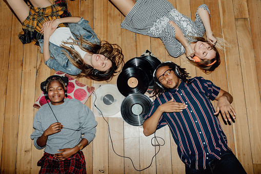 Group of young friends listening to music with vinyls scattered about