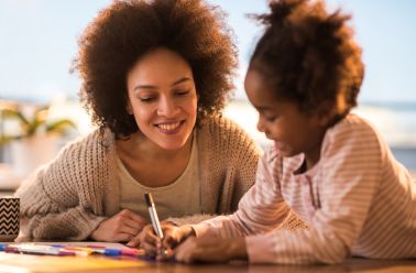 Happy African American mother and daughter spending creative time together.