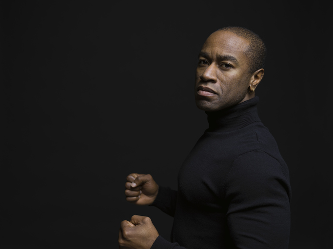 Portrait tough African American man gesturing with fists against black background