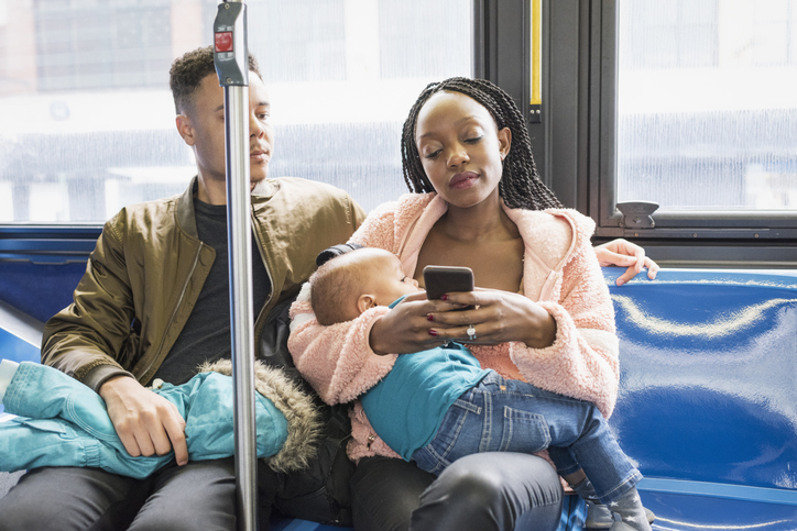 Young mother father and infant riding city bus
