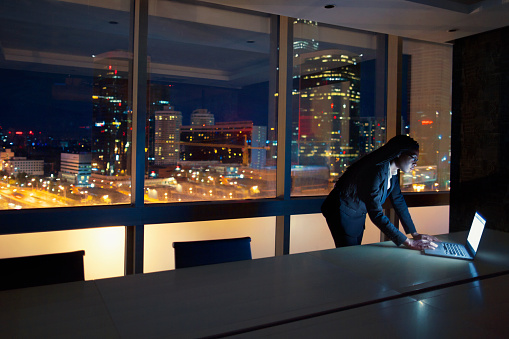 Woman views laptop on table at night