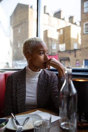 Pensive woman sitting by herself in a restaurant at lunch break