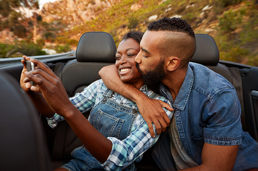 Couple kissing while making selfie in car