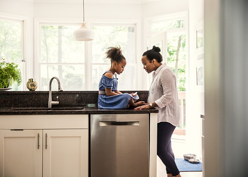 Mother and young daughter talking in kitchen