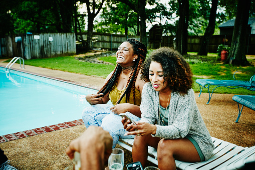 Laughing woman hanging out with friends by pool