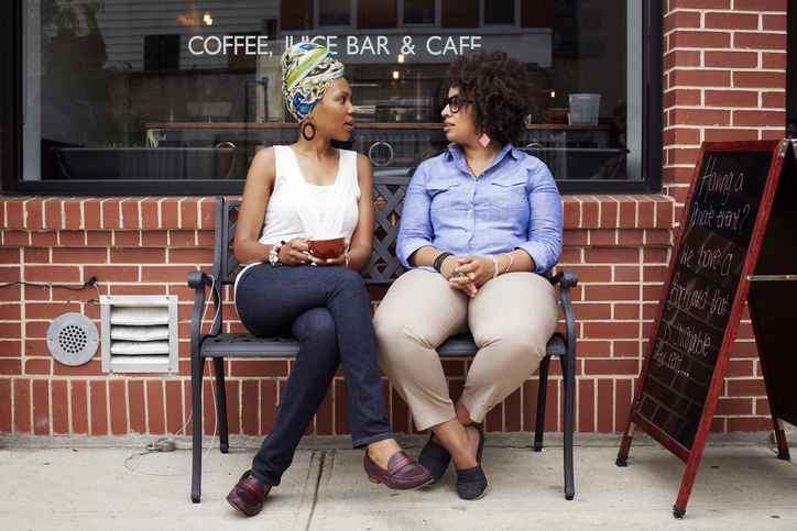 Women talking outside coffee shop on city street