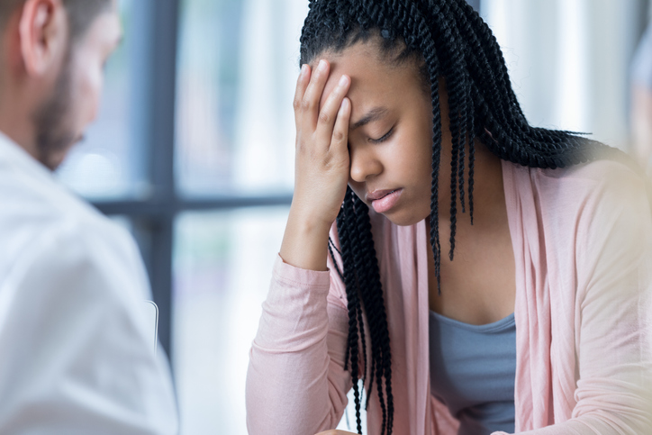 Upset African American teenage girl confides in doctor